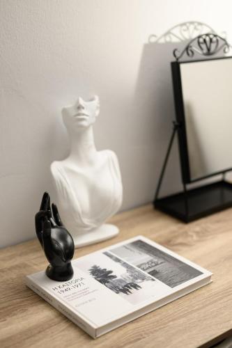 a book on a table with a statue and a mannequin at LakeSide Apartment in Kastoria