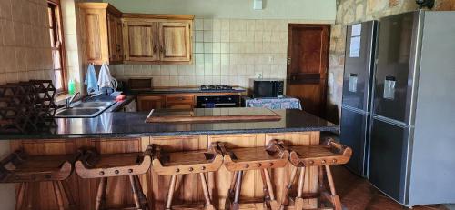 a kitchen with a counter and a refrigerator and stools at Field and Stream in Dullstroom