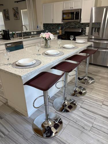 a kitchen with a counter with four bar stools at Elegant family home in Cypress