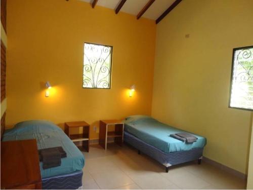 a room with two beds and a table and two windows at Casa Amarilla in Gemastepe