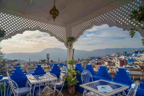 a view of the city from a restaurant with blue tables and chairs at PALACIO AL ANDALUS in Chefchaouene