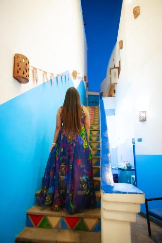 a woman in a dress walking down stairs at DoroKa Nubian House in Aswan