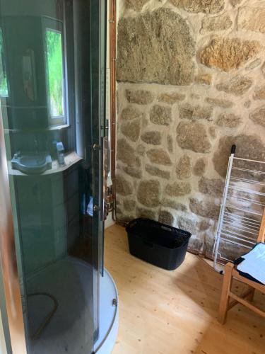 - une douche en verre dans une chambre dotée d'un mur en pierre dans l'établissement Petit chalet en montagne, à Grandrif