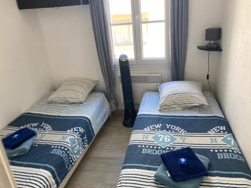 deux lits dans une petite pièce avec une fenêtre dans l'établissement Bandol Studio à deux pas du port, à Bandol
