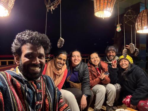 a group of people sitting on a bench at BohOdyssey Hallan a Traditional Village Stay with Panoramic Mountain Views in Nagar