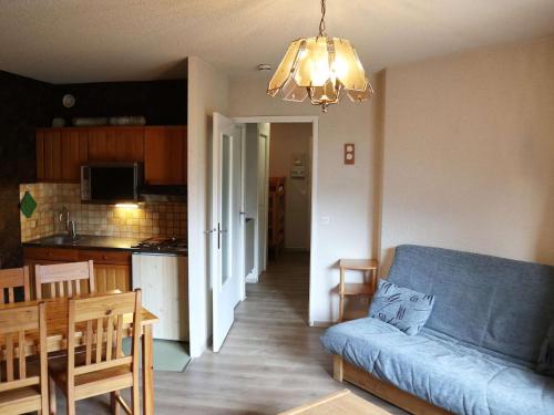 un salon avec un canapé bleu et une cuisine dans l'établissement Studio skis aux pieds pour 4 pers, Place Emile Hodoul - FR-1-322-20, aux Orres