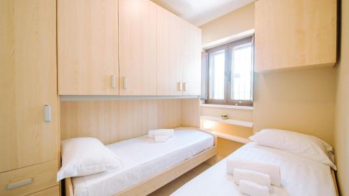 a small room with two beds and a window at TRULLO MALVISCHI - Privacy & Pool in Alberobello