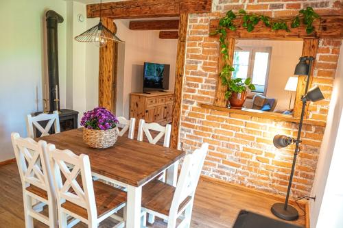 a dining room with a table and a brick wall at Zakątek - Żabi Kraj in Mnich