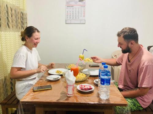 a man and woman sitting at a table eating food at Sinharaja Pitadeniya Villa in Deniyaya