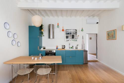 Una cocina con gabinetes azules y una mesa de madera. en Inn Oltremare - appartamento di design a un passo dal centro e dal mare, en Livorno