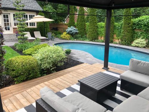 a backyard with a swimming pool and a wooden deck at Garden Suite with Pool and Sauna in Brampton