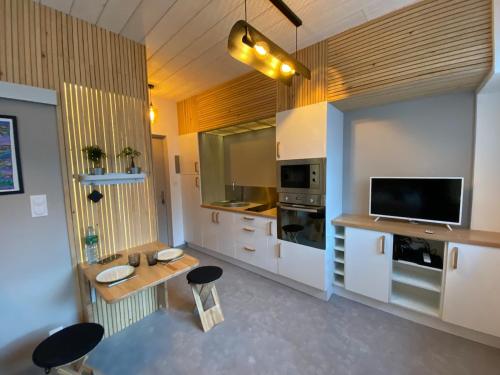 une grande cuisine avec des placards blancs et une télévision dans l'établissement Charmant studio quartier salins 5mn gare routiere, à Clermont-Ferrand