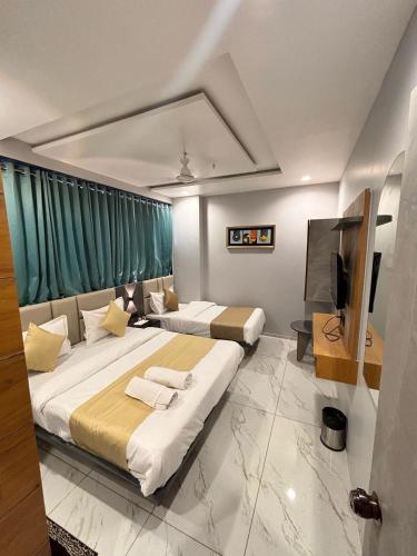 a hotel room with two beds and a television at Hotel Sparsh Inn in Ahmedabad