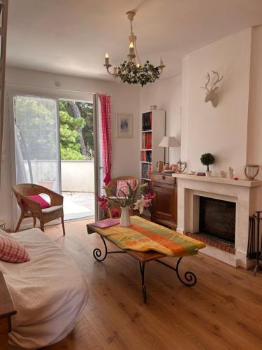 un salon avec une table et une cheminée dans l'établissement Maison Familiale Chaleureuse à Deux Pas de la Plage, à Saint-Brévin-lʼOcéan