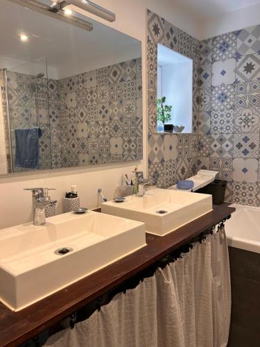 une salle de bain avec deux lavabos, un miroir et une baignoire dans l'établissement Maison Familiale Chaleureuse à Deux Pas de la Plage, à Saint-Brévin-lʼOcéan