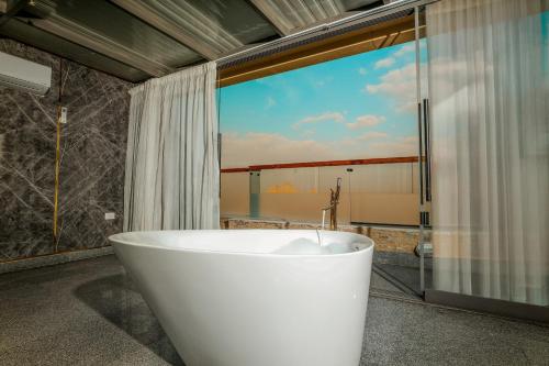 a bath tub in a bathroom with a large window at Sultan Pyramids View INN in Cairo
