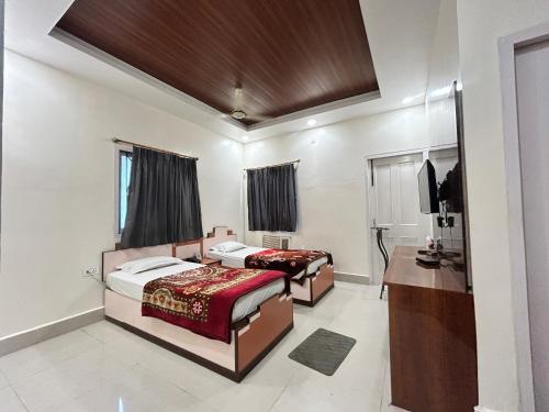 a bedroom with two beds and a desk and a mirror at HOTEL DEBARSHi in Bānkura