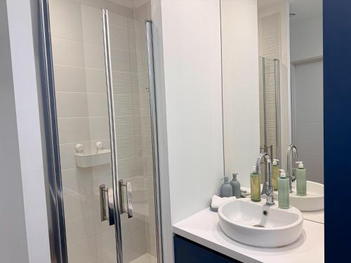 a white bathroom with a sink and a shower at Appartement 2 chambres- 10 mn d'Orléans - Le Nid de la Pointe - in Saint-Pryvé-Saint-Mesmin