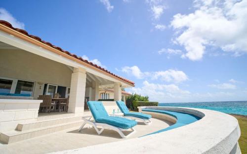 a patio with two lounge chairs and the ocean at Maltese Falcon Villa 3bd by ZenBreak in Saint Philip