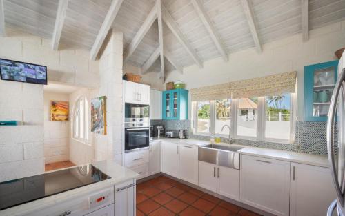a large kitchen with white cabinets and a sink at Maltese Falcon Villa 3bd by ZenBreak in Saint Philip