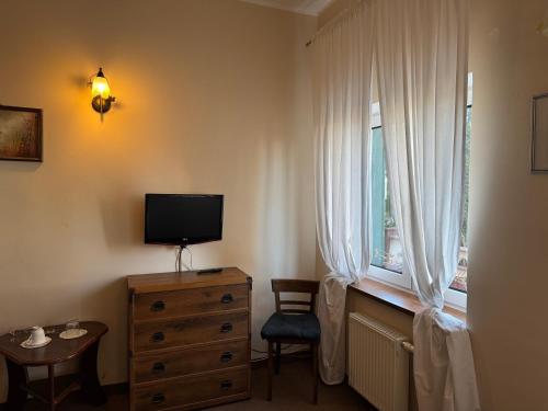 a bedroom with a television and a dresser with a window at Folwark Nadmorska Ostoja in Mechelinki
