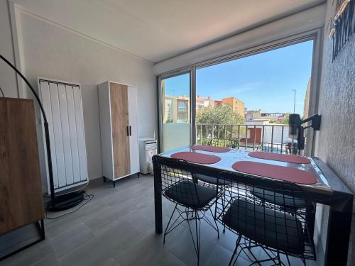 une pièce avec une table et des chaises et une grande fenêtre dans l'établissement Superb apartment 2 min from Richelieu Beach, Cap d'Agde, au Cap d'Agde