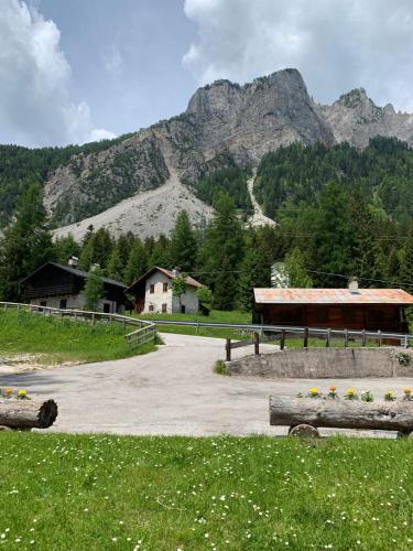 a building in a field with mountains in the background at Dafne Dolomites in Cibiana