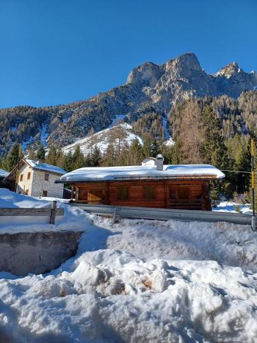 a building covered in snow with mountains in the background at Dafne Dolomites in Cibiana