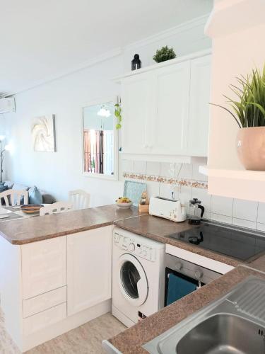 a kitchen with white cabinets and a washer and dryer at La Florida Apartment Near Emerald Isle Complex in Orihuela Costa