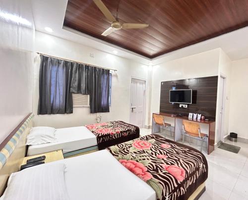 a hotel room with two beds and a desk at HOTEL DEBARSHi in Bānkura