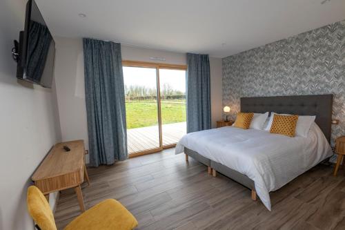 a bedroom with a bed and a sliding glass door at Chez Watersy in Belle-et-Houllefort