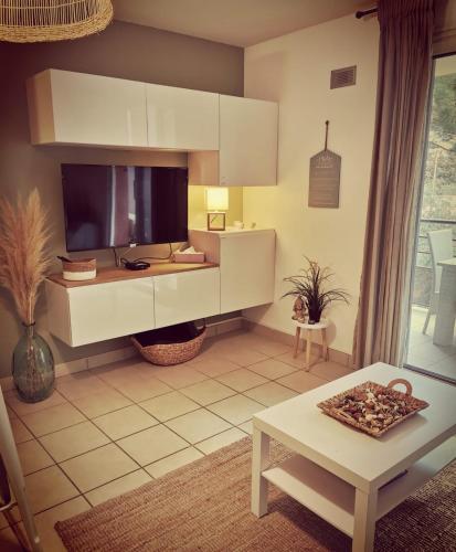 un salon avec une télévision et une table dans l'établissement Cocon de douceur à 10 min de la plage, à Alénya