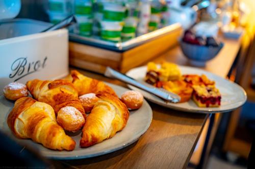 two plates of croissants and pastries on a table at bodenseezeit Apartmenthotel Garni in Lindau