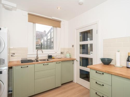 a kitchen with white cabinets and a sink and a window at Charming Family House in Rosewell - Pass the Keys in Edinburgh