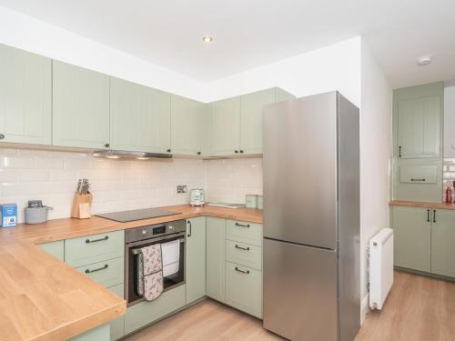 a kitchen with white cabinets and a stainless steel refrigerator at Charming Family House in Rosewell - Pass the Keys in Edinburgh