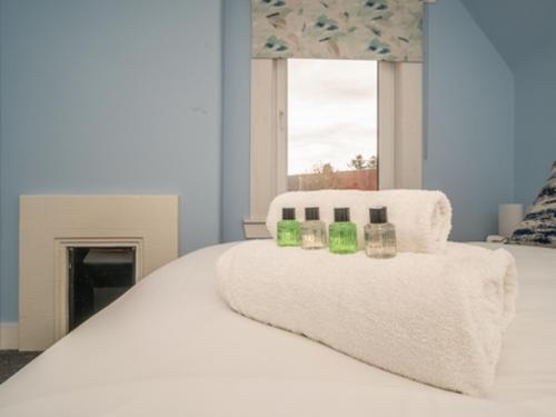 a white bed with green candles on top of it at Charming Family House in Rosewell - Pass the Keys in Edinburgh