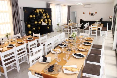 a dining room with a long table and white chairs at The Space Guesthouse Mondlo in Mondlo