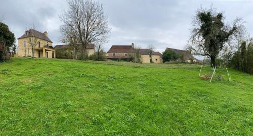 a large grassy field with houses in the background at La porte du jardin in Saint-Aubin-de-Nabirat