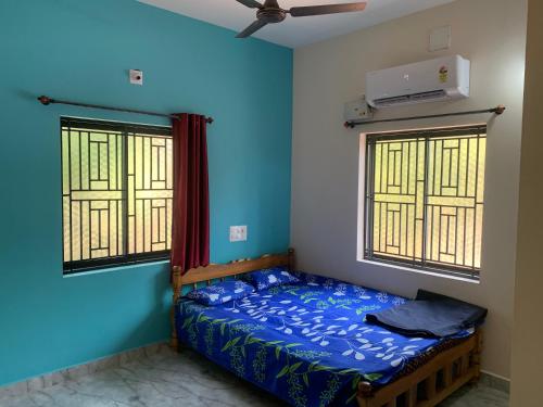 a bed in a room with blue walls and windows at Bethel Homestay Honnavar in Honāvar