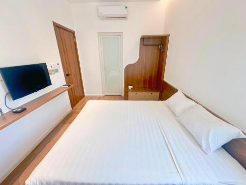 a bedroom with a white bed and a flat screen tv at Le Huynh Mui Ne Hotel in Mui Ne