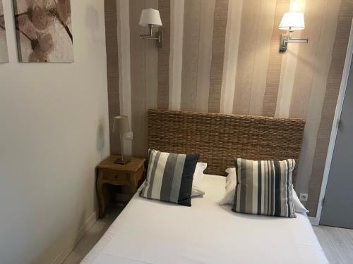 a bedroom with a large white bed with two pillows at Hotel Des Falaises in Villers-sur-Mer