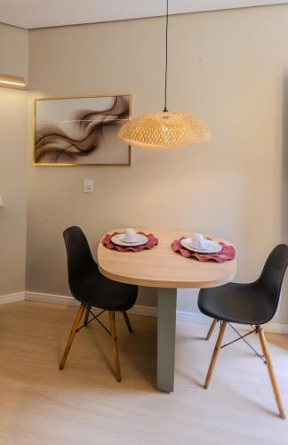 a dining room table with two chairs and a lamp at Pousada Natribus Rosa in Praia do Rosa
