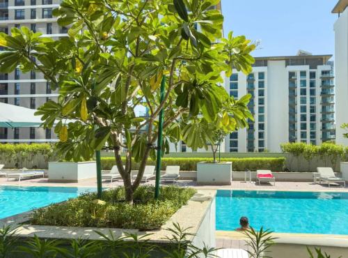 a palm tree next to a swimming pool at a hotel at Luxury 2BR in Sobha Hartland in Dubai