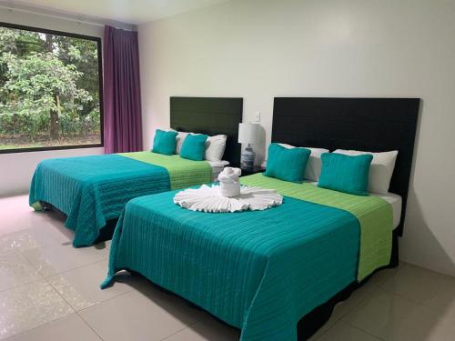 a bedroom with two beds with blue and green sheets at Hotel Los Rios in Guácimo