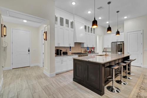 a kitchen with white cabinets and a large island with bar stools at Sunny Stay Orlando Queen Room 5 with Shared Bath in Orlando