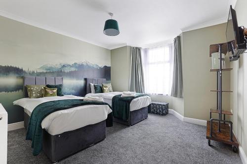 a bedroom with two beds and a painting on the wall at OnSiteStays - Stylish 5 bedroom house with 3 bathrooms in Dartford