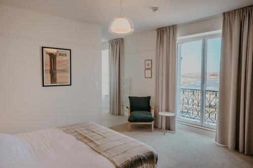 a bedroom with a bed and a chair and a window at Dek in Landunvez
