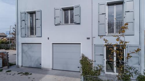 a white building with two garage doors and two windows at Bellaria Palace - In the hearth of Motor Valley in Modena