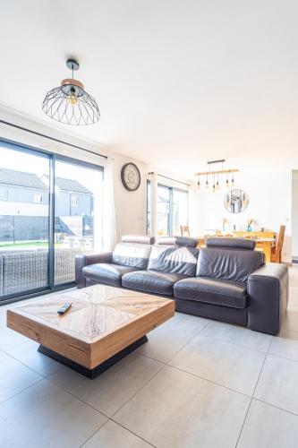 un salon avec un canapé et une table basse dans l'établissement La Maison du Bonheur - Private heated pool, à Heuqueville