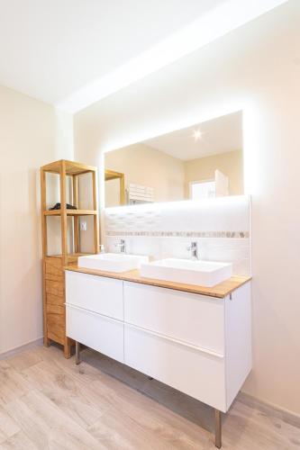 une salle de bain avec deux lavabos et un miroir dans l'établissement La Maison du Bonheur - Private heated pool, à Heuqueville